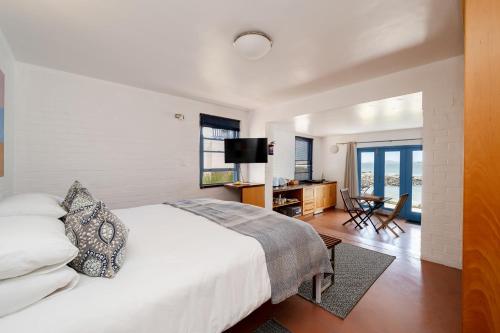 a bedroom with a white bed and a television at Seehuis Studios in Langebaan