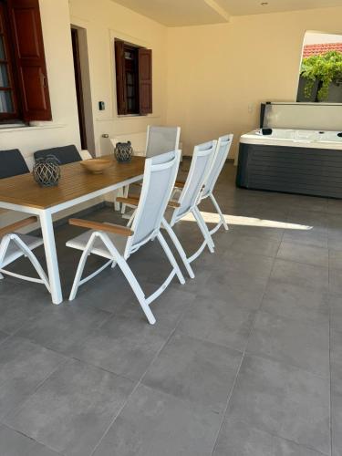 a dining room with a table and white chairs at Amaryllis Beach House in Lartos