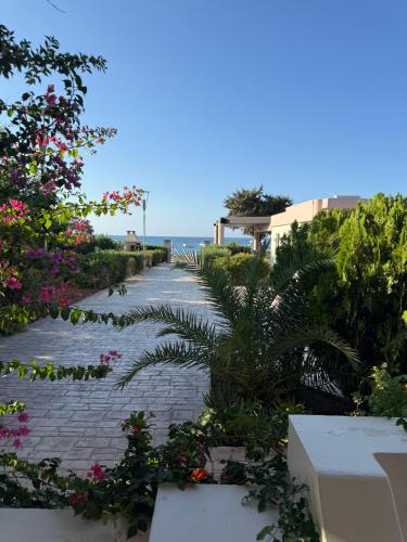 a stone pathway with flowers and the ocean in the background at Amaryllis Beach House in Lartos