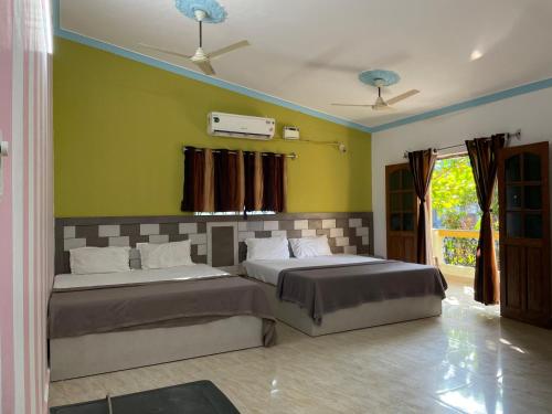 two beds in a room with green walls at Cardozo beach house in Calangute