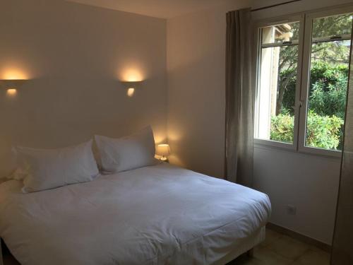 Una cama blanca en una habitación con ventana. en Villa des carassins, en Saint-Rémy-de-Provence