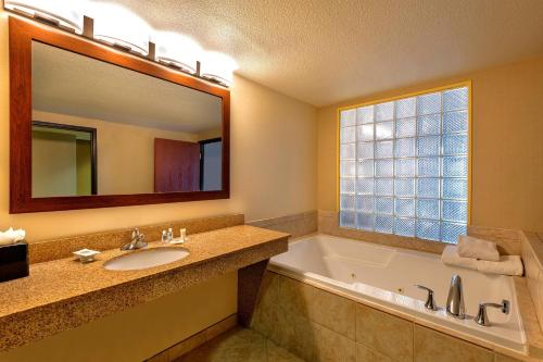 a bathroom with a tub and a sink and a mirror at Comfort Suites Goodyear-West Phoenix in Goodyear