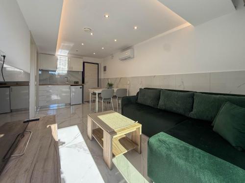 a living room with a green couch and a table at MELISSA Suites By SDR in Paralia Katerinis