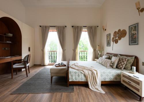 a bedroom with a bed and a desk in it at LohonoStays Villa Floresta in Assagao
