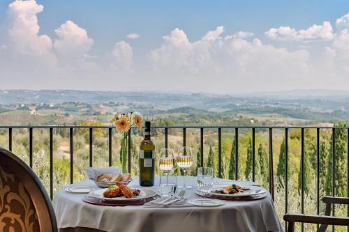 a table with plates of food and wine glasses at Villasanpaolo Resort & Spa in San Gimignano