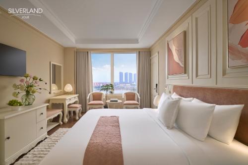 a hotel room with a large white bed and a window at Silverland Jolie Hotel in Ho Chi Minh City