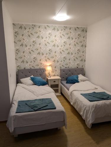 a bedroom with two beds and a table with a lamp at Lägenhet nära naturen Pralinette BB in Nykroppa