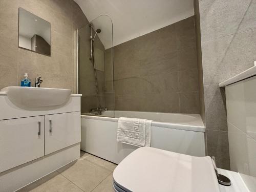 a bathroom with a sink and a toilet and a tub at Egham Modern Two Bedroom Apartment in Egham