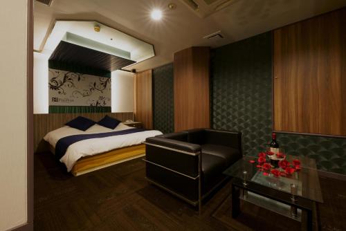 a bedroom with a bed and a chair and a table at Hotel Pierrot Izumiotsu -Adult Only in Izumiotsu