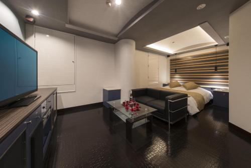 a living room with a couch and a bed at Hotel Pierrot Izumiotsu -Adult Only in Izumiotsu