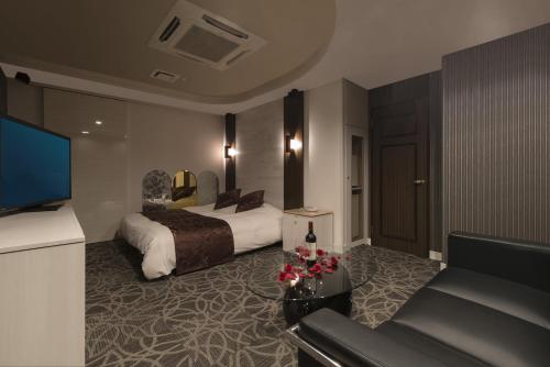 a hotel room with a bed and a couch at Hotel Pierrot Izumiotsu -Adult Only in Izumiotsu