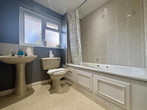 a bathroom with a toilet and a sink and a tub at Spacious 5 Bedroom House Addlestone in Addlestone