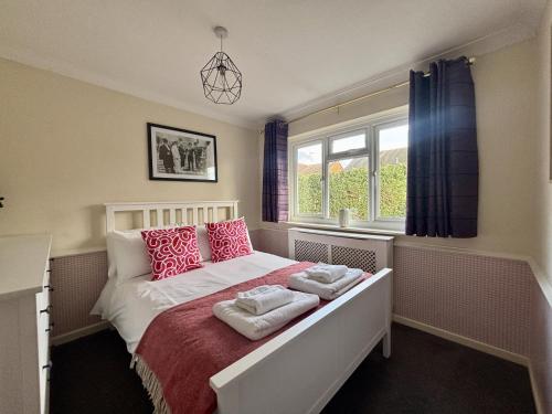 a bedroom with a bed with red and white pillows at Spacious 5 Bedroom House Addlestone in Addlestone