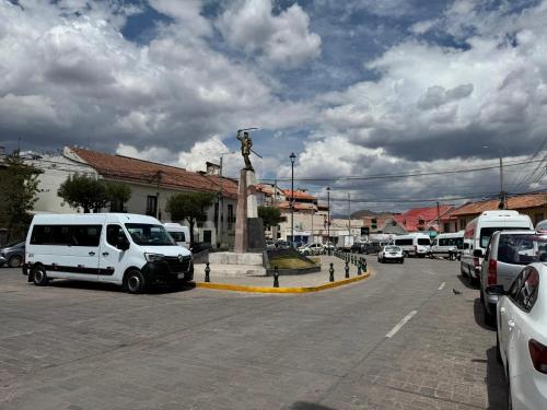 a street with cars parked next to a statue at Templo de la Luna Pardo in Cusco