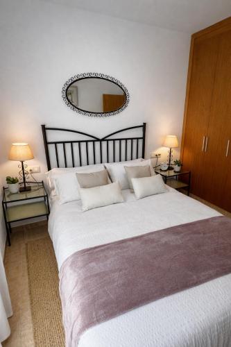 a bedroom with a large white bed with a large mirror at RelaxMaria in Sant Carles de la Ràpita