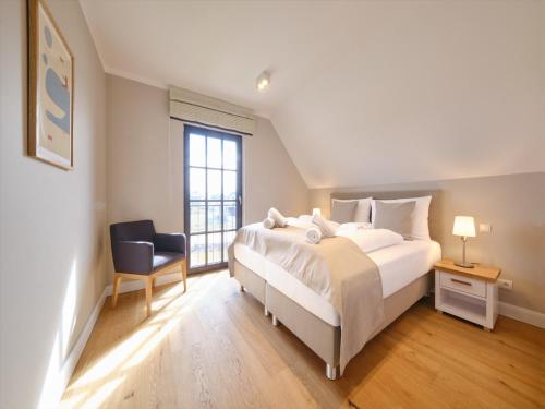a bedroom with a large white bed and a chair at Reetland am Meer - LuxusPlus Reetdachvilla mit 4 Schlafzimmern, Außensauna, Loungebereich und Kamin H09 in Dranske