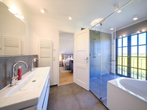 a bathroom with a shower and a sink and a tub at Reetland am Meer - LuxusPlus Reetdachvilla mit 4 Schlafzimmern, Außensauna, Loungebereich und Kamin H09 in Dranske