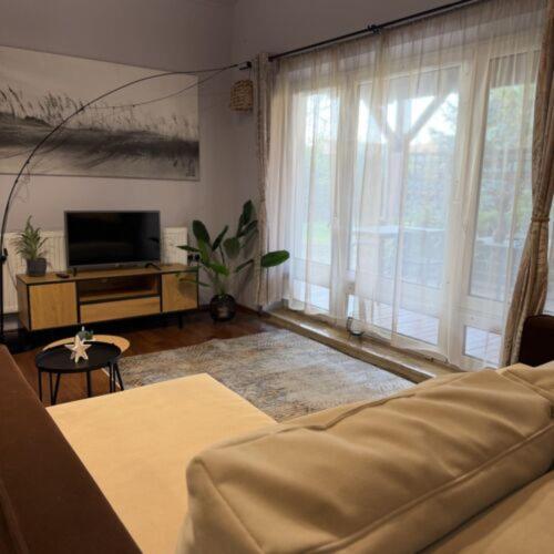 a living room with a couch and a large window at Charlie porta in Abádszalók