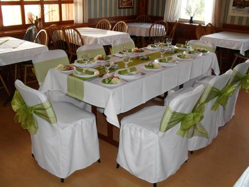 un comedor con mesas blancas y sillas con comida. en Dedesi Vendégház Zalalövő, en Zalalövő