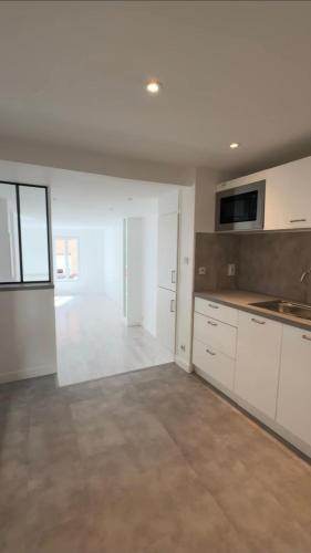 an empty kitchen with white cabinets and a large room at large downtown studio in Corbeil-Essonnes