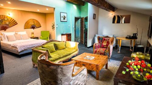 a living room with a bed and a couch and a table at Villa Troletti, hôtel particulier de luxe en Provence in L'Isle-sur-la-Sorgue
