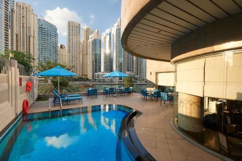 a swimming pool in a building with tables and chairs at City Premiere Marina Hotel Apartments in Dubai