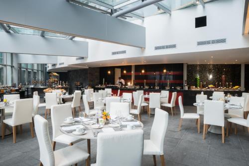 a dining room with white tables and white chairs at Hotel Las Americas Golden Tower Panamá in Panama City