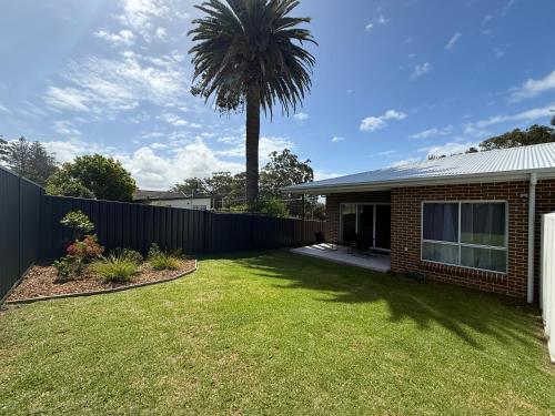a house with a palm tree in the yard at Family Holiday Home Ulladulla in Ulladulla
