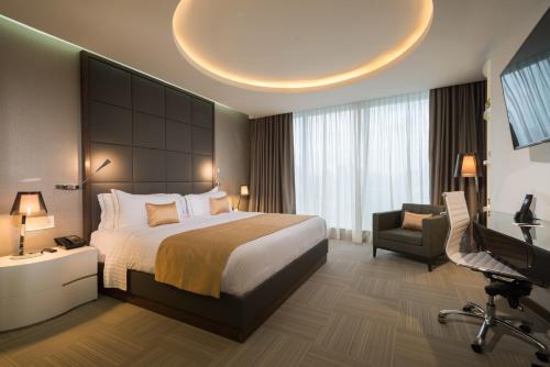 a bedroom with a bed and a desk and a television at Hotel Las Americas Golden Tower Panamá in Panama City