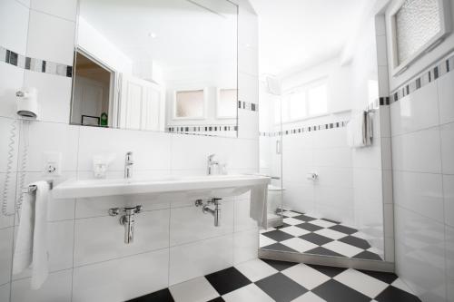 a white bathroom with a sink and a checkered floor at Hotel Helvetie Montreux in Montreux