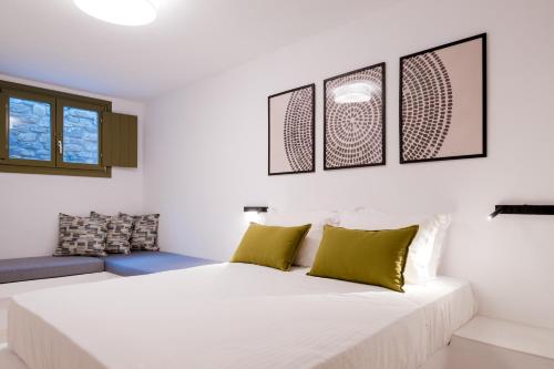 a bedroom with a large white bed with green pillows at White Cliff Villas Paros in Ambelas