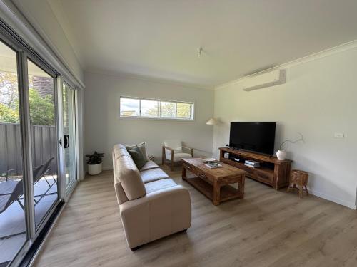 a living room with a couch and a tv at Family Holiday Home Ulladulla in Ulladulla