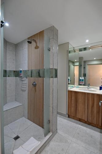 a bathroom with a shower and a sink at Lagoon Beach Hotel & Spa in Cape Town
