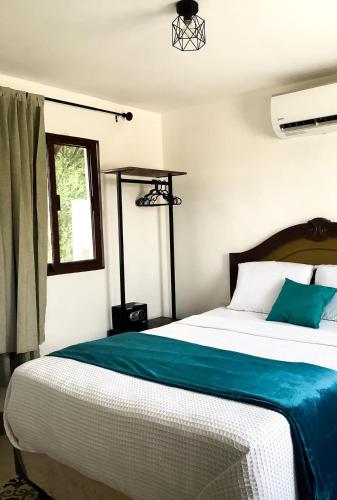 a bedroom with a large bed with blue sheets and a window at Casa Bahareque Merida in Mérida