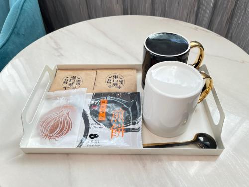 a tray with a cup and a coffee mug on a table at Wind Sea Hill Inn in Hengchun South Gate