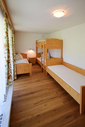 a room with two bunk beds and wooden floors at Gästehaus Waltl in Krimml