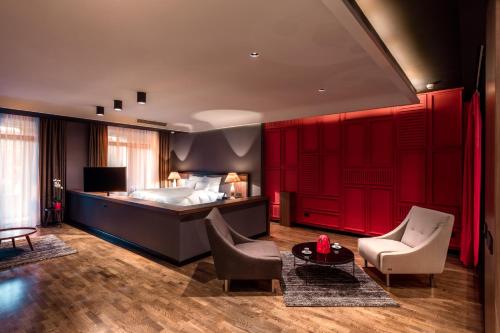 a bedroom with a bed with red doors and chairs at Park Hotel & Spa in Skopje