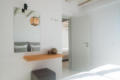a room with white walls and a table and a bench at White Cliff Villas Paros in Ambelas