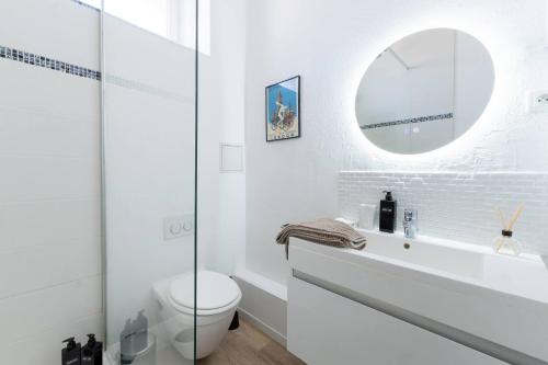 une salle de bain blanche avec toilettes et miroir dans l'établissement Le Nautique, à Valence