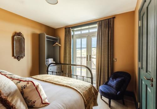 a bedroom with a bed and a chair and a window at Dumbarnie East Cottage in Kirkton of Largo