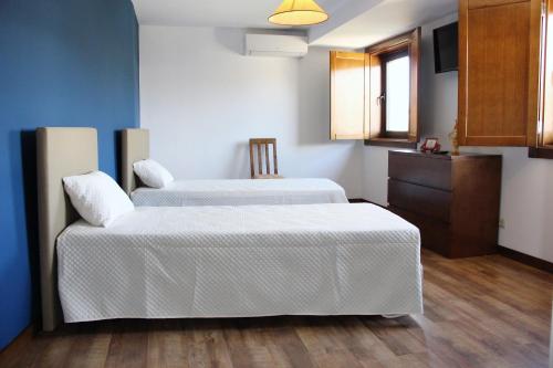 Duas camas num quarto com paredes azuis e pisos em madeira em Casa do Ferrador em São Pedro de Vale do Conde