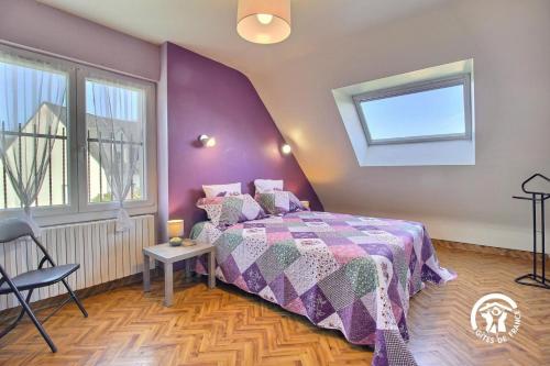 a bedroom with a bed with a purple wall at Le clos du bas in Noyal-Muzillac