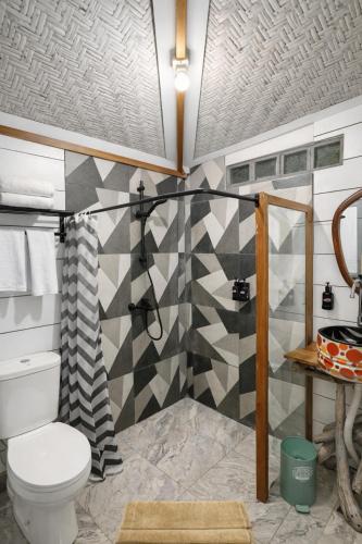 a bathroom with a toilet and a geometric wall at Maza Lodge & Spa in Kejajar