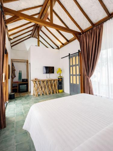 a bedroom with a white bed and a tv at Maza Lodge & Spa in Kejajar