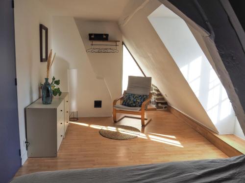 a attic room with a chair and a window at Chez Philomène in Aubusson