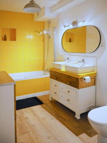 a yellow bathroom with a sink and a tub at Chez Philomène in Aubusson
