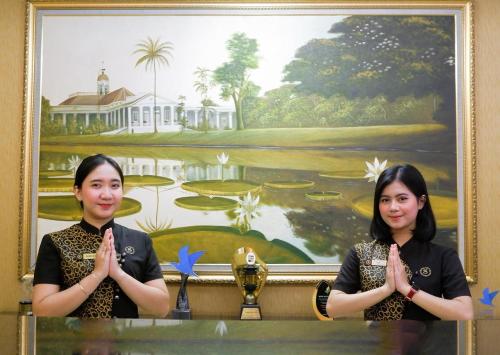 two women are praying in front of a painting at Grand Savero Hotel Bogor in Bogor