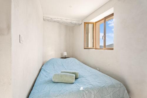 a bed in a white room with a window at Le Cocon de la Combe - Maisonnette pour 4p in Coursegoules