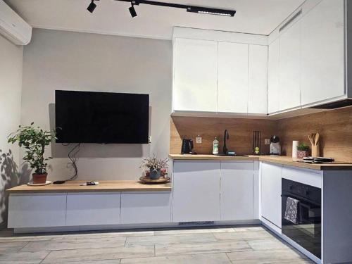 a kitchen with white cabinets and a flat screen tv at Dębowe Wzgórze 8-12 in Złotów