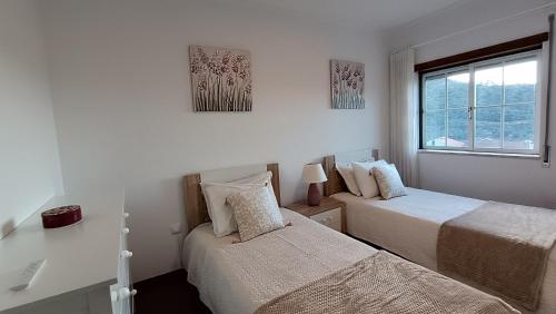 a bedroom with two beds and a window at Lousã's Brown & White in Lousã